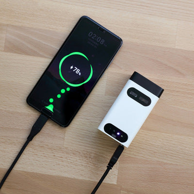 Black phone with green projected interface next to a white laser keyboard projector